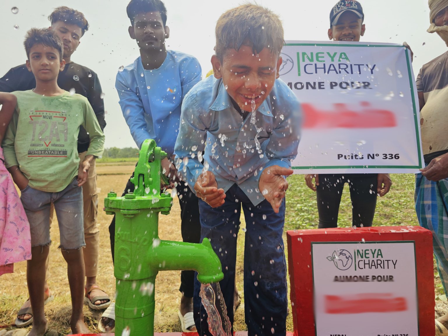 Un enfant boit l'eau fraîche d'un puits construit par NEYA Charity